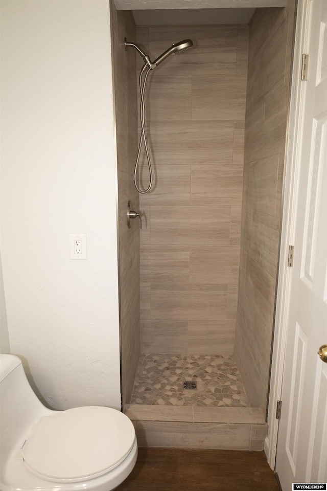 bathroom featuring a tile shower and toilet