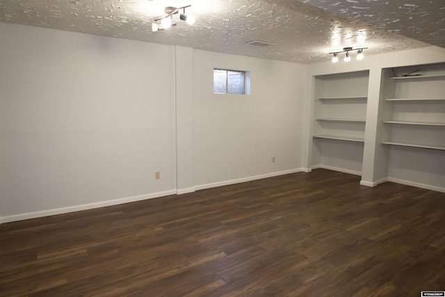 basement with dark hardwood / wood-style flooring, a textured ceiling, and built in features