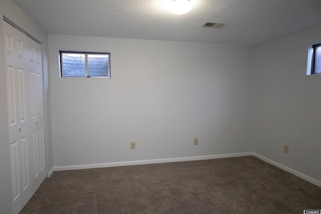 empty room featuring dark colored carpet and a textured ceiling