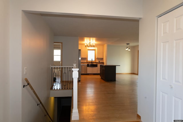 hallway with sink, hardwood / wood-style floors, and an inviting chandelier