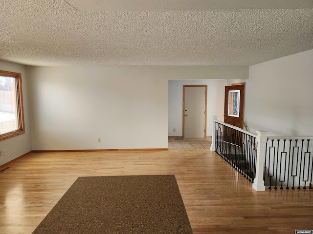 spare room with a textured ceiling and light hardwood / wood-style floors