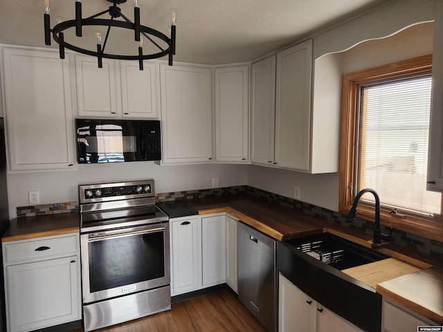 kitchen featuring white cabinetry, sink, stainless steel appliances, an inviting chandelier, and dark hardwood / wood-style flooring