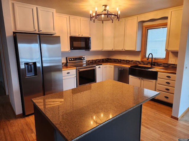 kitchen with white cabinets, stainless steel appliances, and dark stone countertops