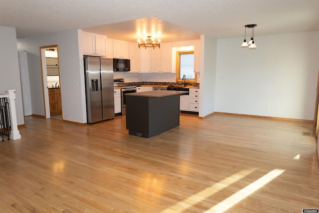 kitchen featuring appliances with stainless steel finishes, pendant lighting, white cabinets, light hardwood / wood-style floors, and a kitchen island