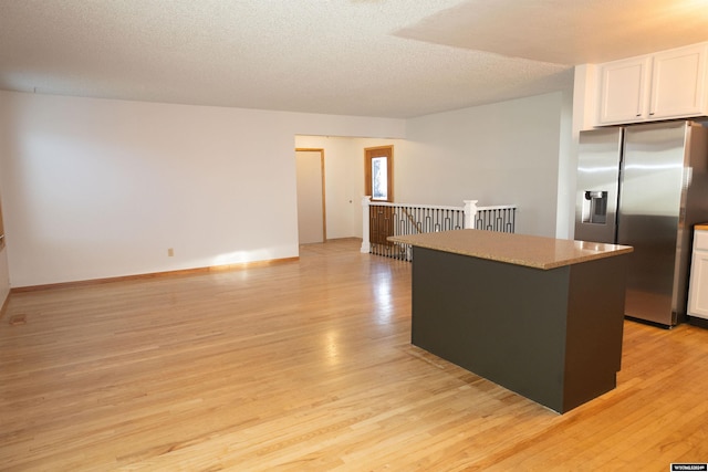 kitchen featuring white cabinets, light hardwood / wood-style floors, a textured ceiling, a kitchen island, and stainless steel fridge with ice dispenser