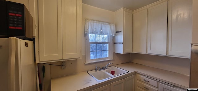 kitchen featuring white cabinets, white fridge, and sink