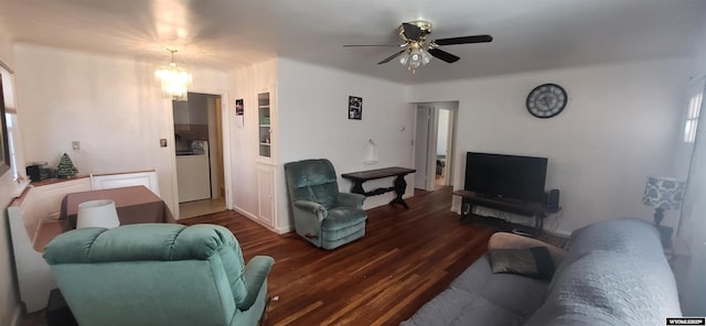 living room featuring dark wood-type flooring, ceiling fan with notable chandelier, and washer / dryer