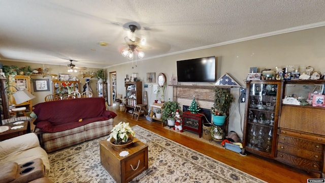 living room featuring a textured ceiling, ceiling fan, ornamental molding, and hardwood / wood-style floors