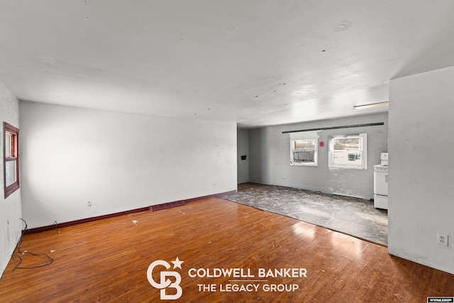 empty room with visible vents, concrete block wall, baseboards, and wood-type flooring