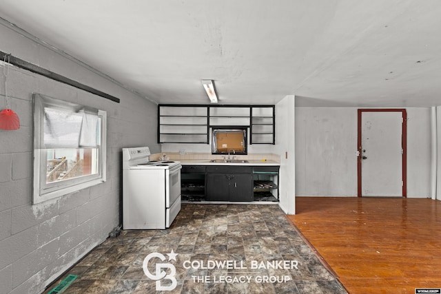 kitchen with a sink, light countertops, concrete block wall, and white electric stove