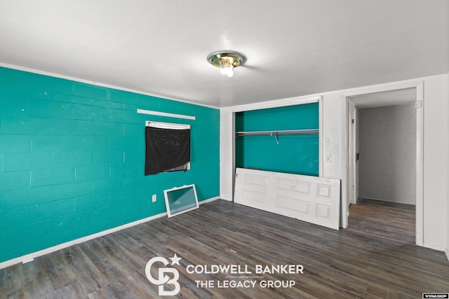 spare room with wood finished floors and concrete block wall