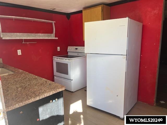 kitchen with light wood-type flooring, visible vents, white appliances, and light countertops