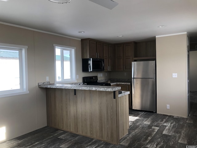 kitchen featuring stainless steel refrigerator, dark wood-type flooring, kitchen peninsula, black range, and ornamental molding