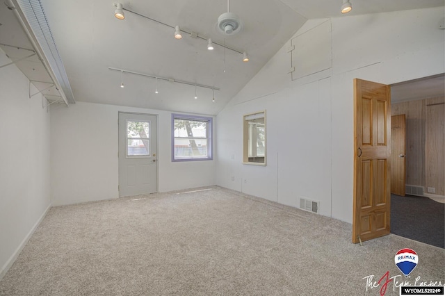 carpeted empty room with high vaulted ceiling