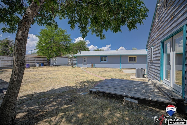 view of yard with central air condition unit, a deck, and a storage unit