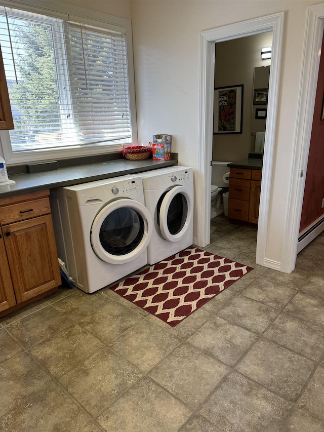 washroom featuring washing machine and dryer, cabinets, and a baseboard heating unit