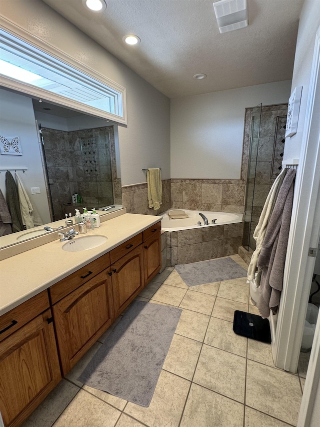 bathroom featuring tile patterned floors, separate shower and tub, vanity, and a textured ceiling