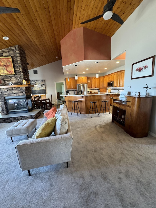 carpeted living room with ceiling fan, wooden ceiling, a fireplace, and high vaulted ceiling