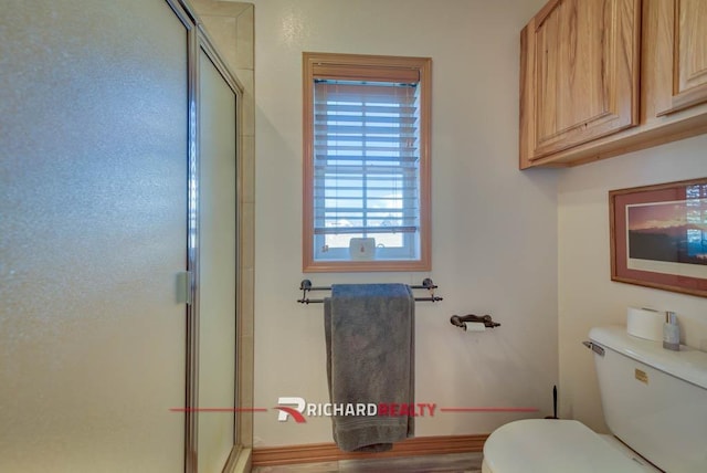 bathroom with a shower with shower door and toilet