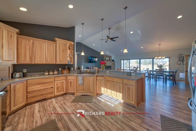 kitchen with light brown cabinets, kitchen peninsula, hanging light fixtures, and vaulted ceiling