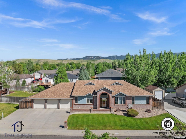 ranch-style home featuring a mountain view, a garage, and a front lawn