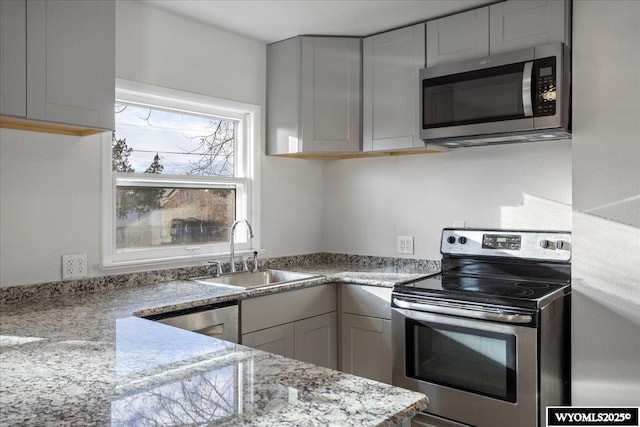 kitchen with light stone countertops, sink, and appliances with stainless steel finishes