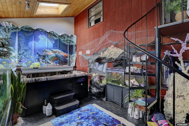 misc room featuring a skylight, wooden ceiling, and wood walls