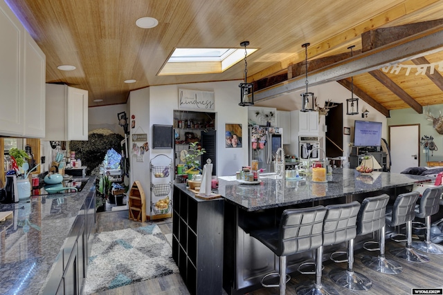 kitchen with white cabinetry, wooden ceiling, dark stone countertops, a spacious island, and pendant lighting