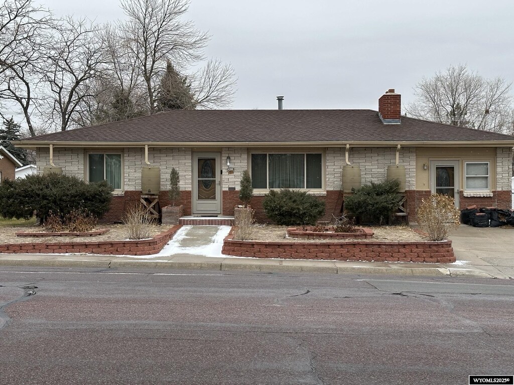 2833 Main St, Torrington, WY 82240 - ranch-style house featuring roof with shingles, a chimney, and brick siding