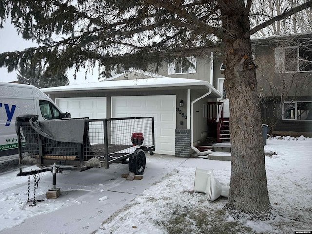 snow covered back of property featuring a garage