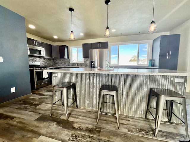 kitchen featuring backsplash, a kitchen breakfast bar, stainless steel appliances, and decorative light fixtures