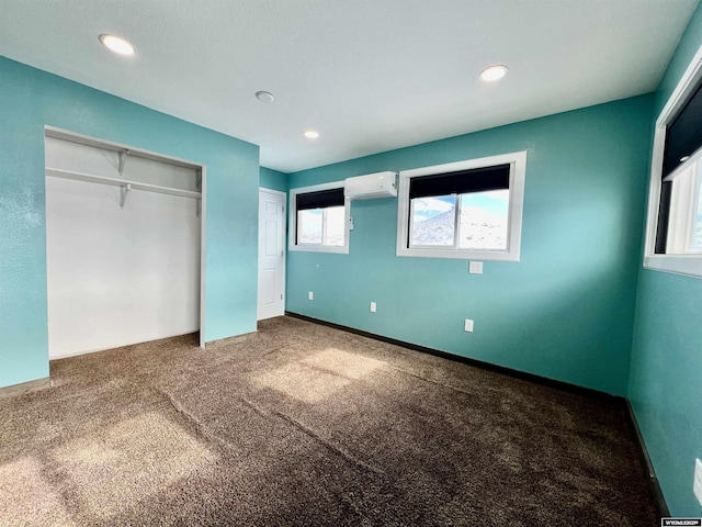 unfurnished bedroom with a wall mounted AC and carpet