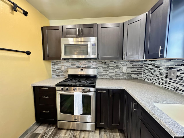 kitchen featuring hardwood / wood-style floors, backsplash, stainless steel appliances, and dark brown cabinets