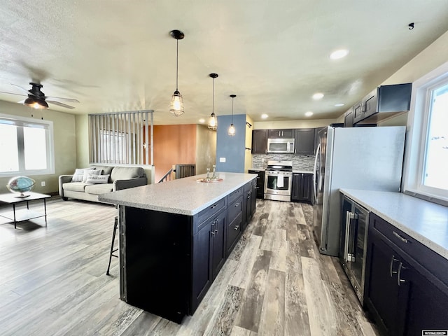 kitchen with appliances with stainless steel finishes, backsplash, a kitchen island, hanging light fixtures, and a breakfast bar area