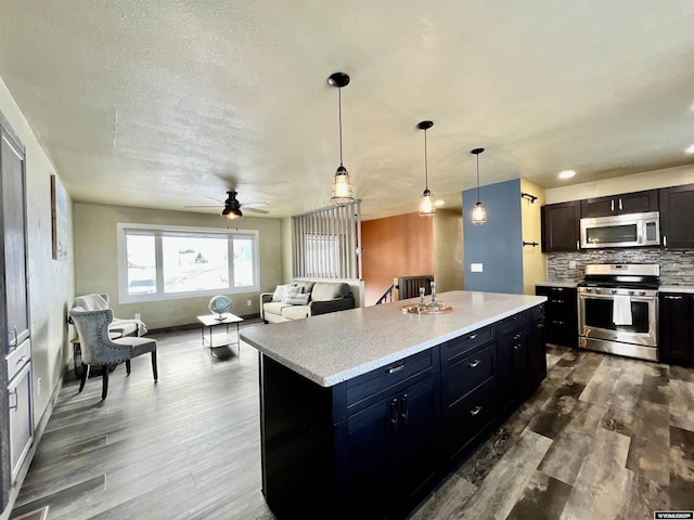 kitchen with ceiling fan, a center island, tasteful backsplash, pendant lighting, and appliances with stainless steel finishes