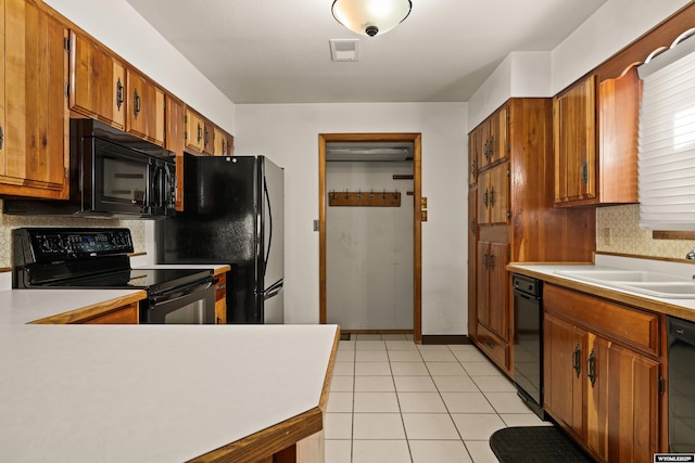 kitchen with light tile patterned flooring, sink, tasteful backsplash, and black appliances