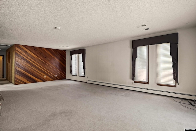 carpeted spare room with a baseboard radiator, a textured ceiling, and wood walls