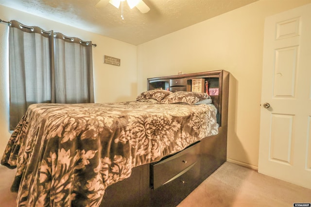 carpeted bedroom featuring ceiling fan and a textured ceiling