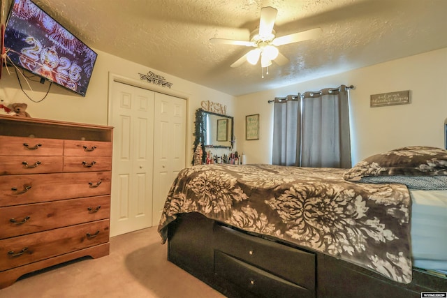 bedroom with ceiling fan, a closet, light carpet, and a textured ceiling