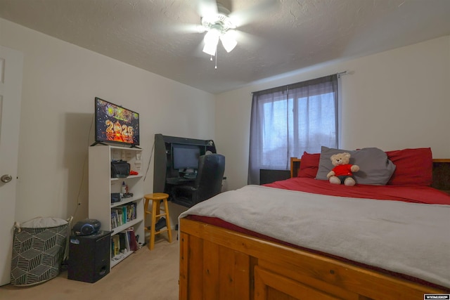 bedroom with ceiling fan, light colored carpet, and a textured ceiling