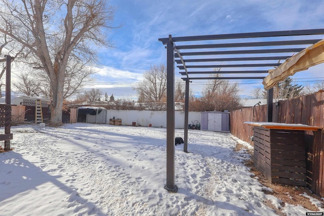 snowy yard featuring a pergola and a storage unit