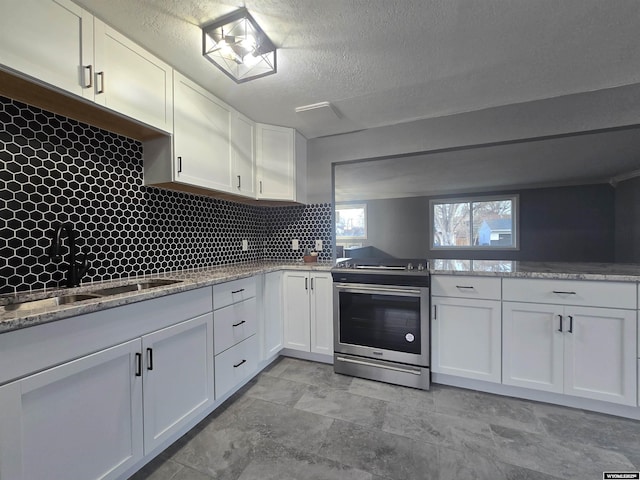 kitchen with stainless steel range with electric stovetop, backsplash, white cabinets, sink, and a textured ceiling