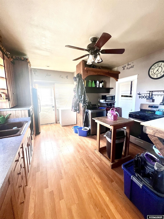 kitchen featuring appliances with stainless steel finishes, light wood-type flooring, washing machine and dryer, and sink