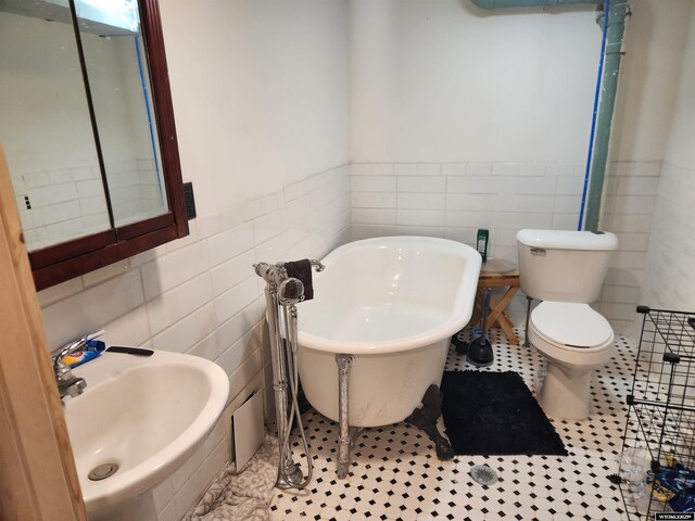 bathroom featuring sink, tile walls, a tub to relax in, tile patterned floors, and toilet