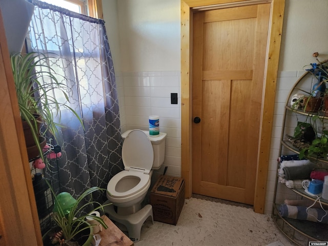 bathroom featuring tile walls and toilet