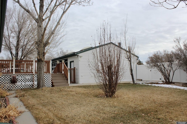 view of side of home featuring a lawn and a wooden deck