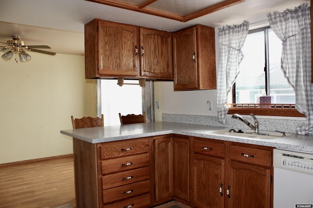 kitchen featuring ceiling fan, sink, kitchen peninsula, white dishwasher, and light wood-type flooring