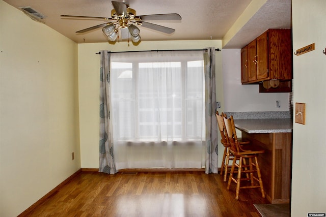 dining space with ceiling fan, light wood-type flooring, and a textured ceiling