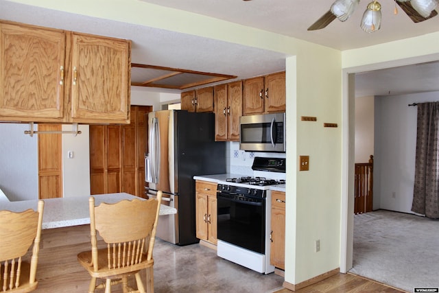 kitchen featuring decorative backsplash, light hardwood / wood-style floors, stainless steel appliances, and ceiling fan