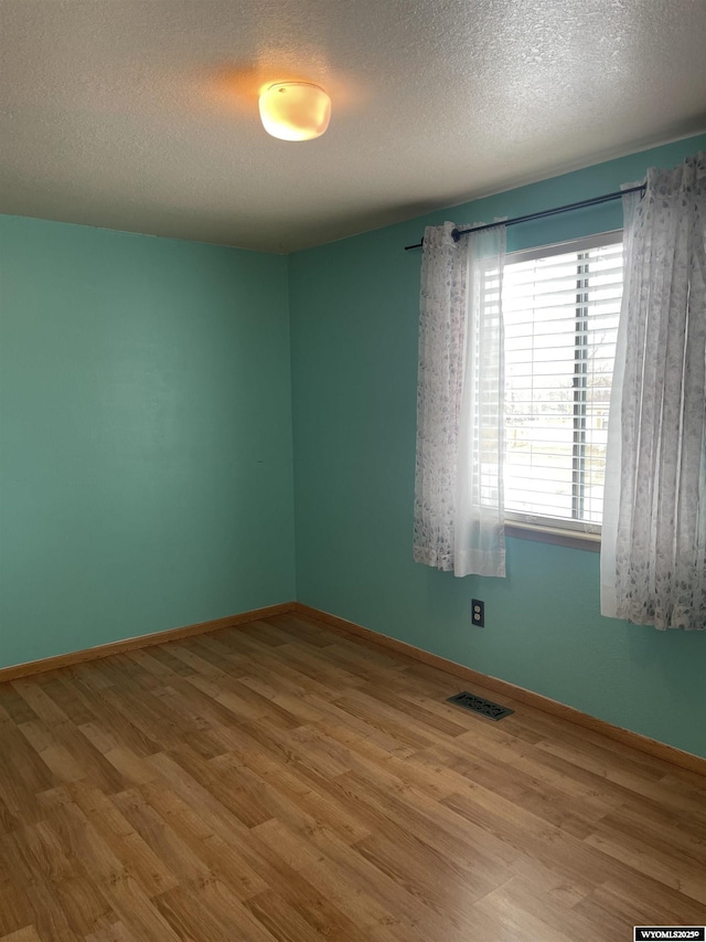 spare room with hardwood / wood-style floors and a textured ceiling